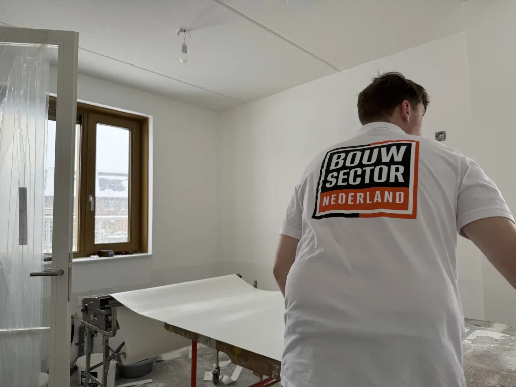 Behanger in een wit shirt trekt een baan van de plaktafel in een lege kamer